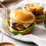 a close up of an air fryer turkey burger with lettuce, cheese, and onion and another turkey burger behind it without a top bun.