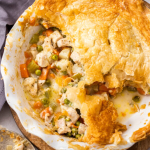 a pie plate with veggies and turkey topped with a puff pastry crust.