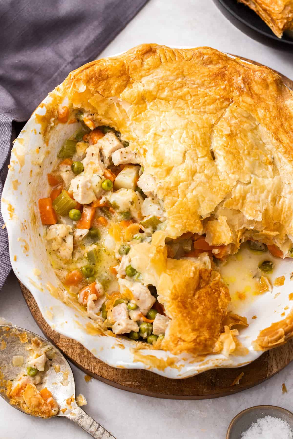 a pie plate with veggies and turkey topped with a puff pastry crust.