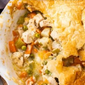 a pie plate with veggies and turkey topped with a puff pastry crust.