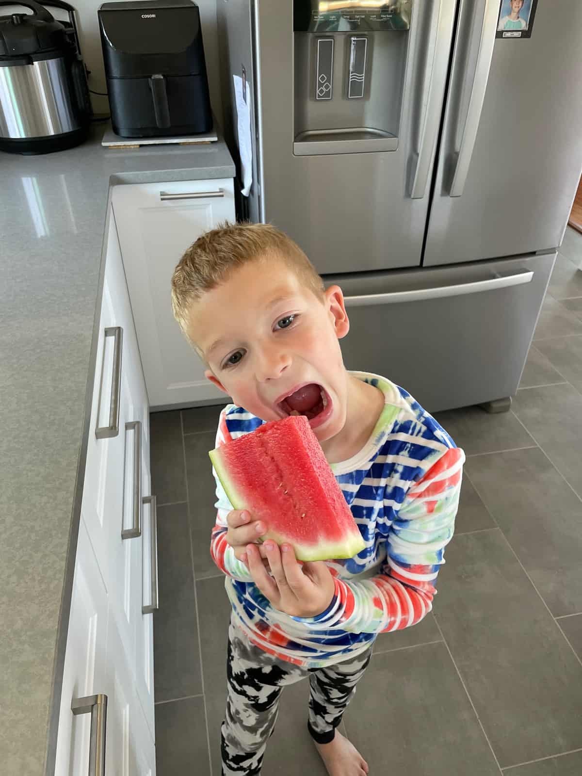 a boy in jammies holding a slice of watermelon
