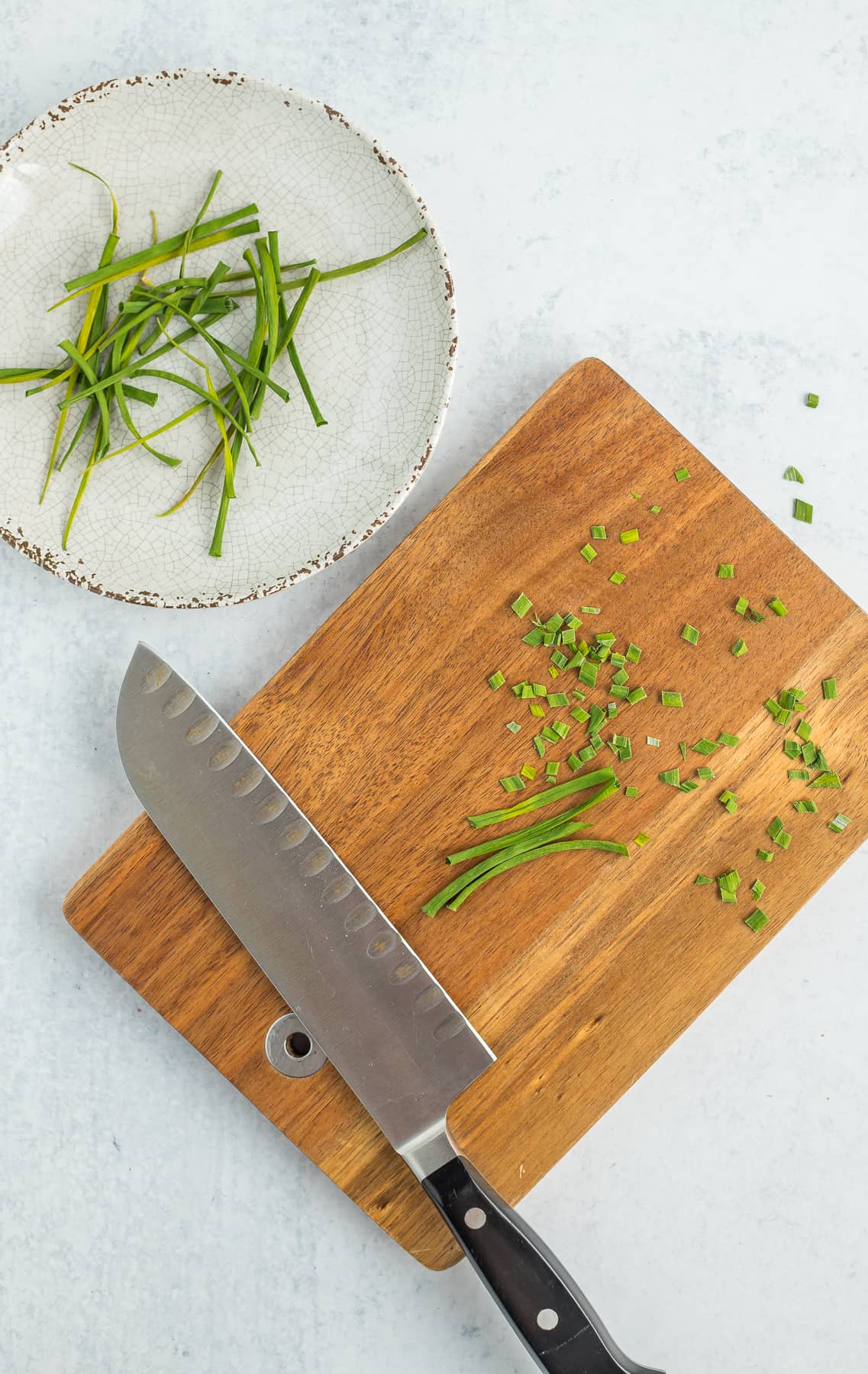 a knife and cutting board with chopped chives.