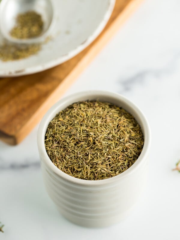 a small grey dish filled with dehydrated thyme on a white board.