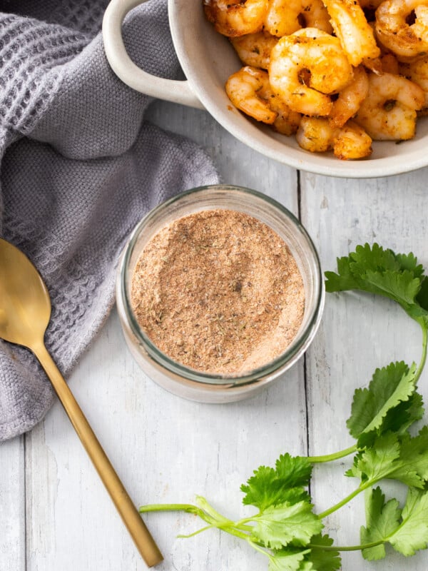 a small dish of homemade seafood seasoning and white bowl with grilled shrimp.