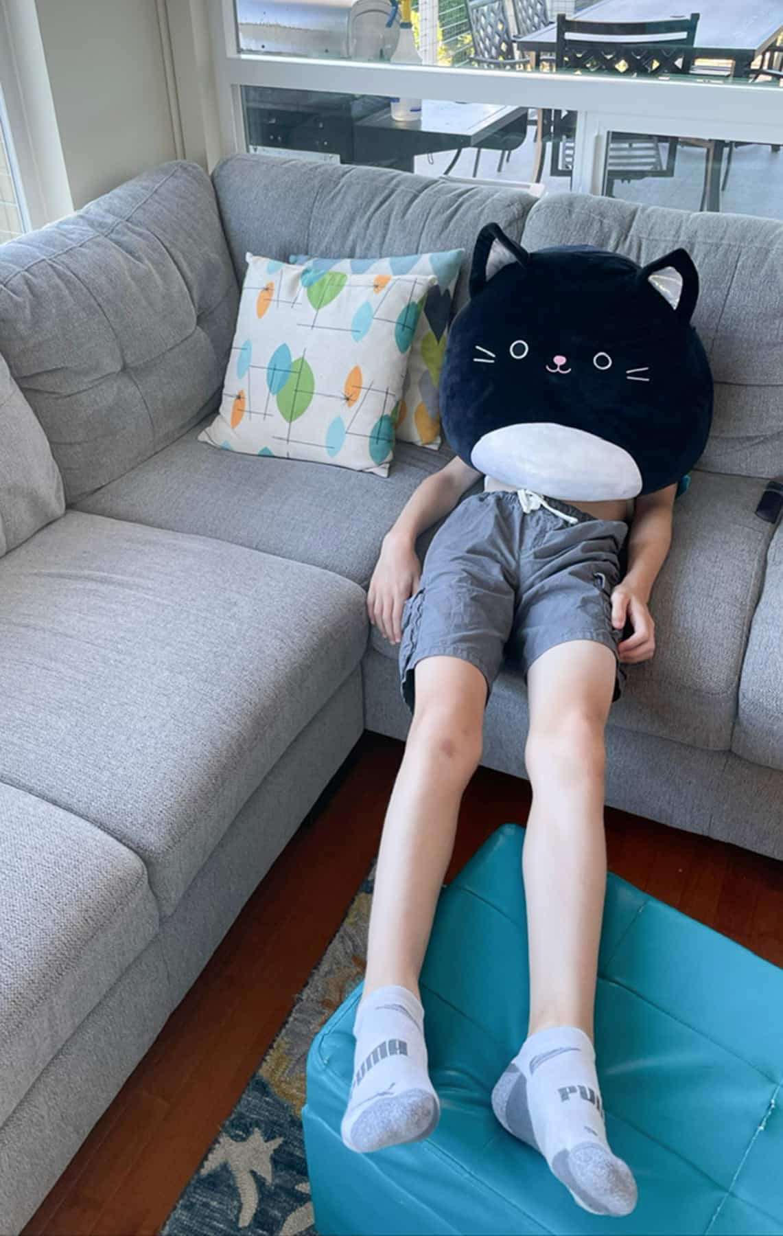 a kid laying on a couch with a stuffed cat.