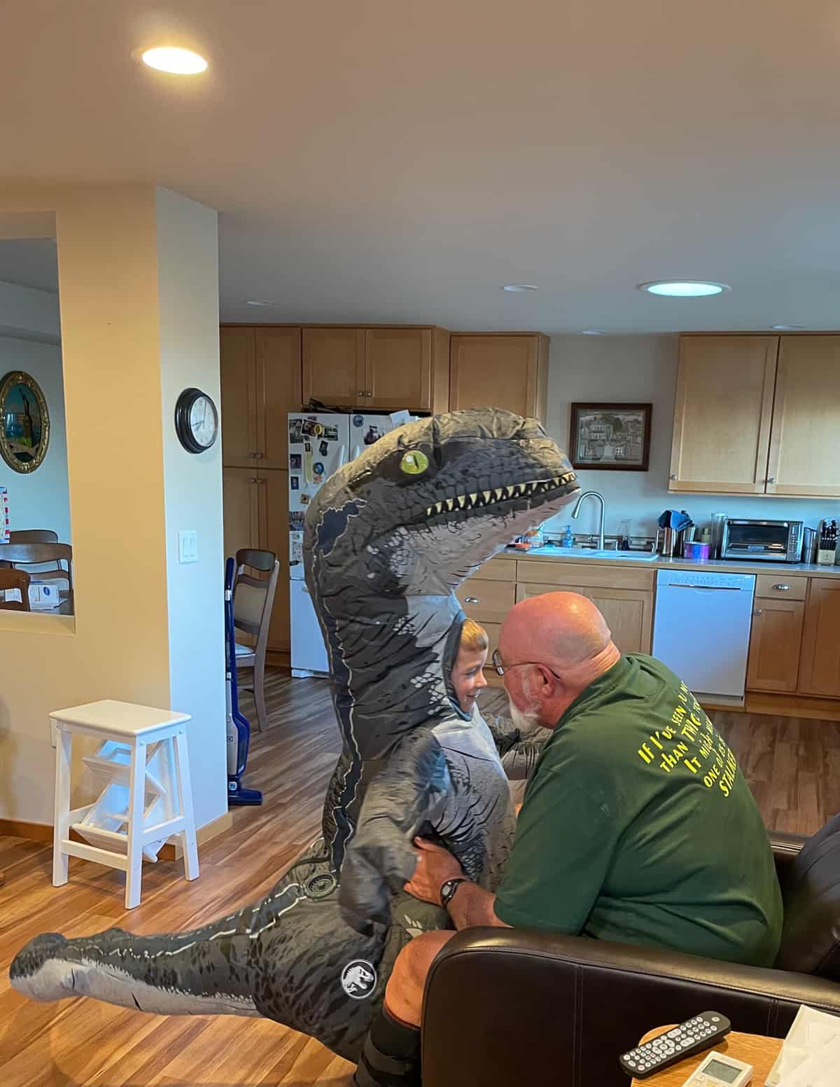 a boy in a dinosaur costume hugging a grandpa.
