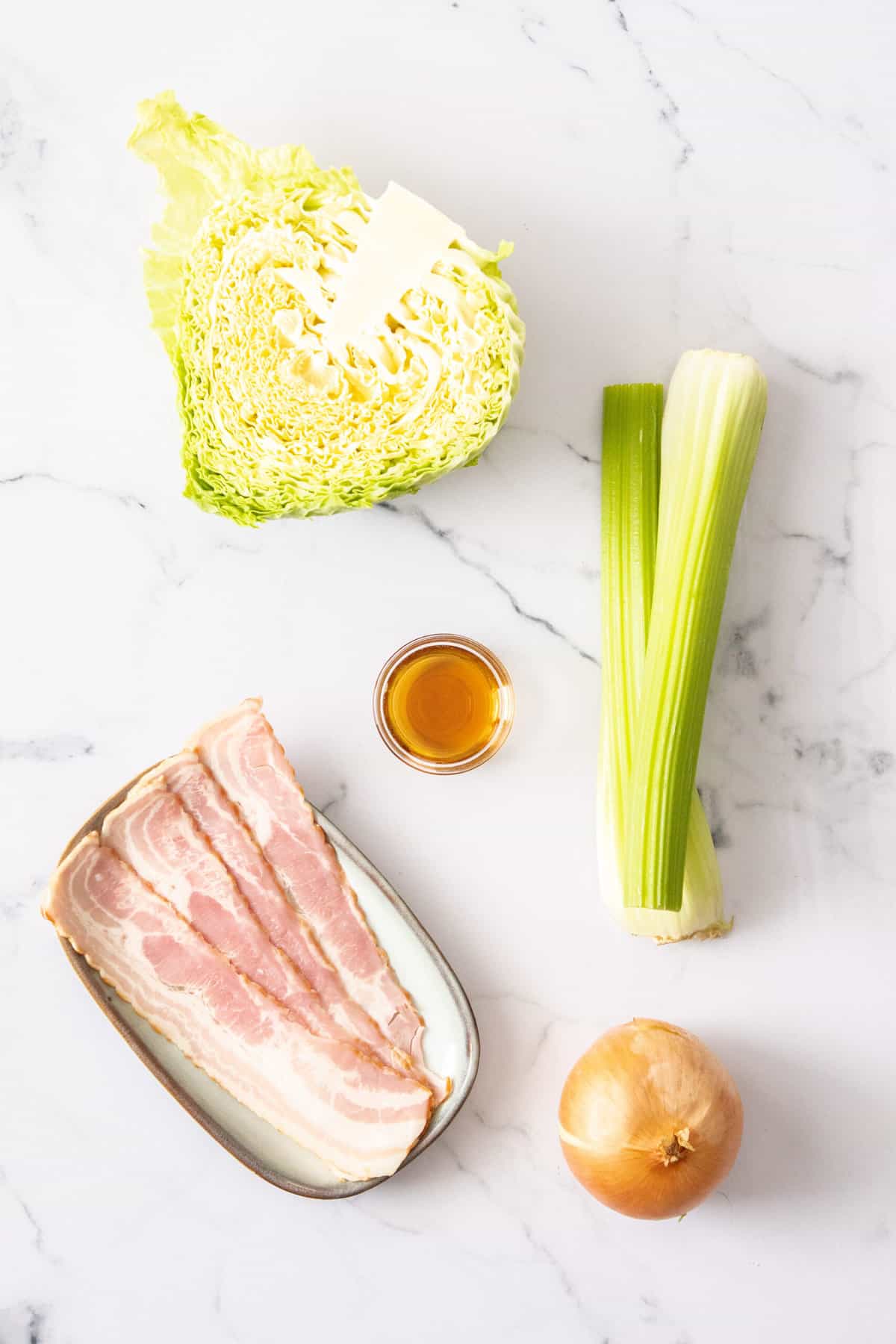 bacon, celery, onion, sesame oil, and cabbage on a white background.