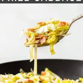 a spoonful of sautéed cabbage and bacon hovering over a black bowl.