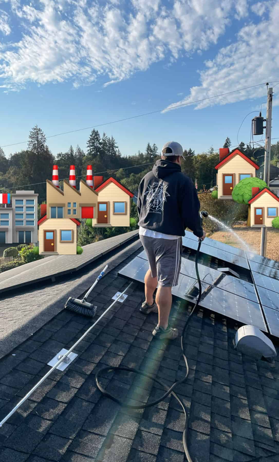 a man on a roof with a hose cleaning solar panels.