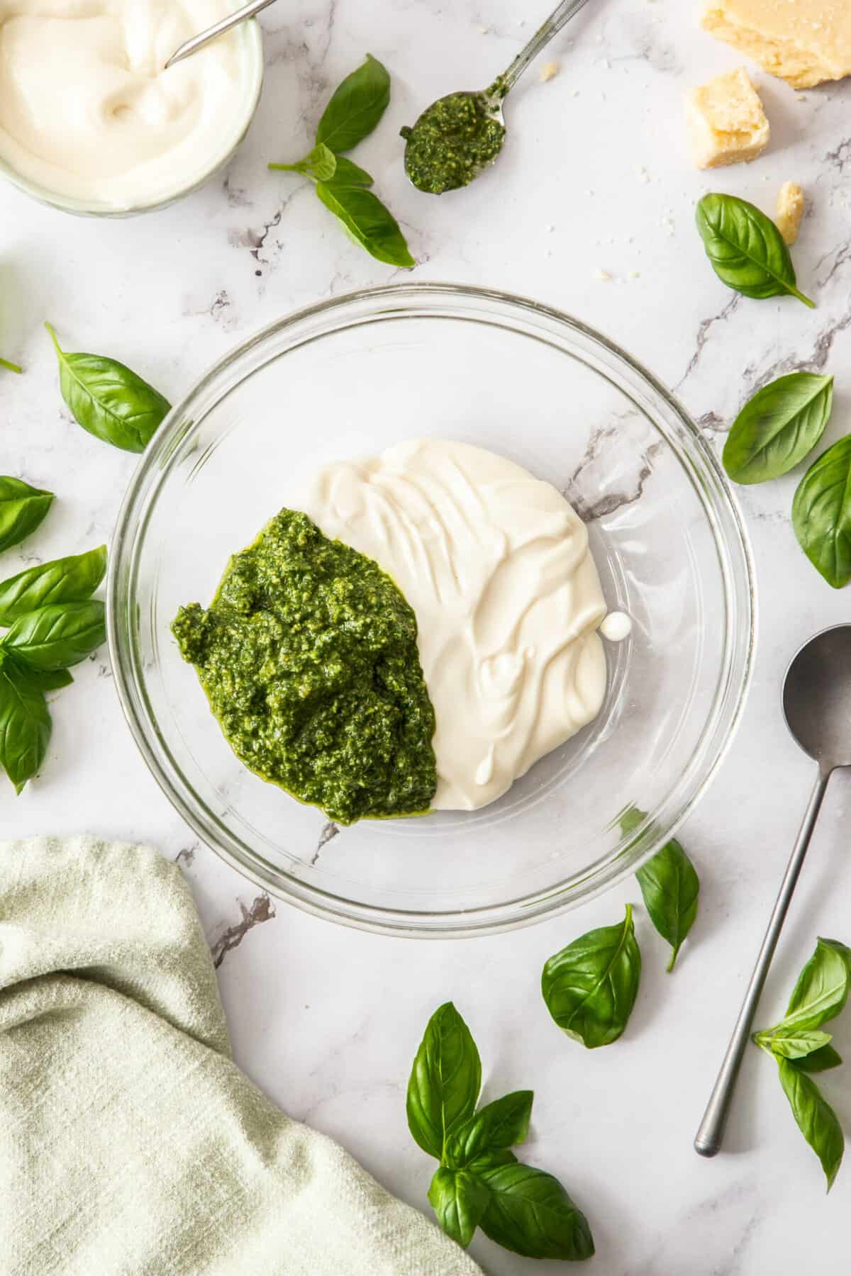 a glass bowl half filled with mayo and half filled with pesto.