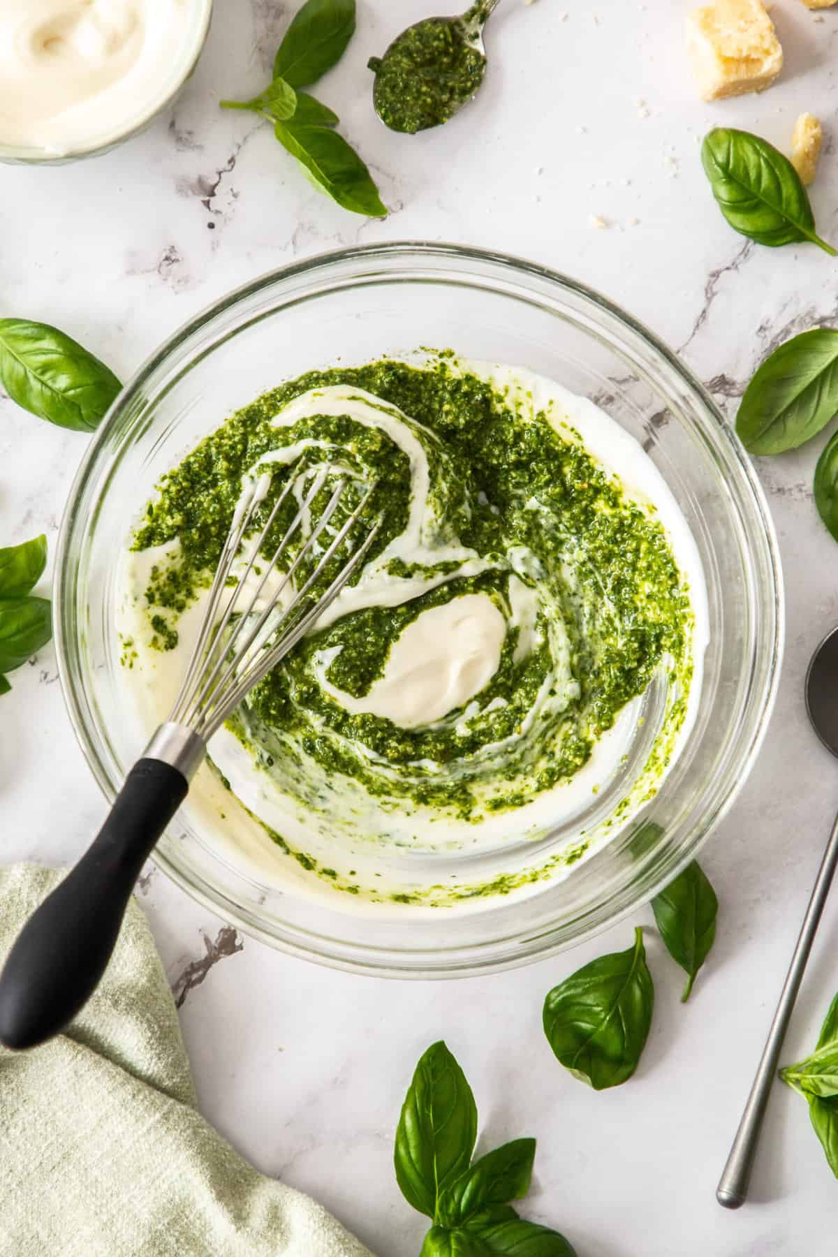 a glass bowl of pesto mayo being mixed.