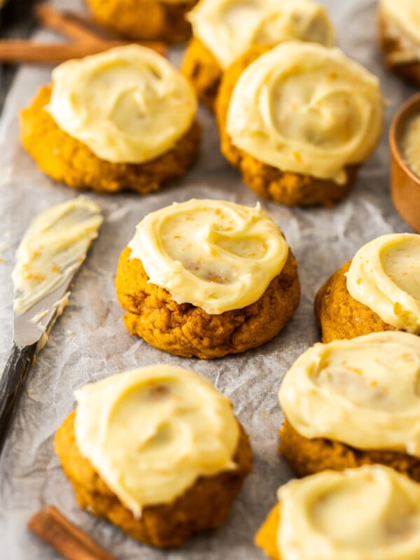 cookies with cream cheese frosting and a knife on parchment.