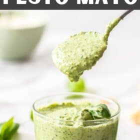 a small glass jar of pesto mayo with a spoon in it.