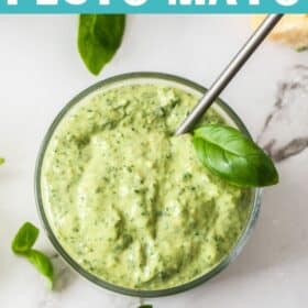 a small glass jar of pesto mayo with a spoon in it.