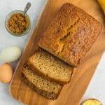 an overhead shot of sliced brown sugar banana bread on a wooden cutting board with a dish of brown sugar.