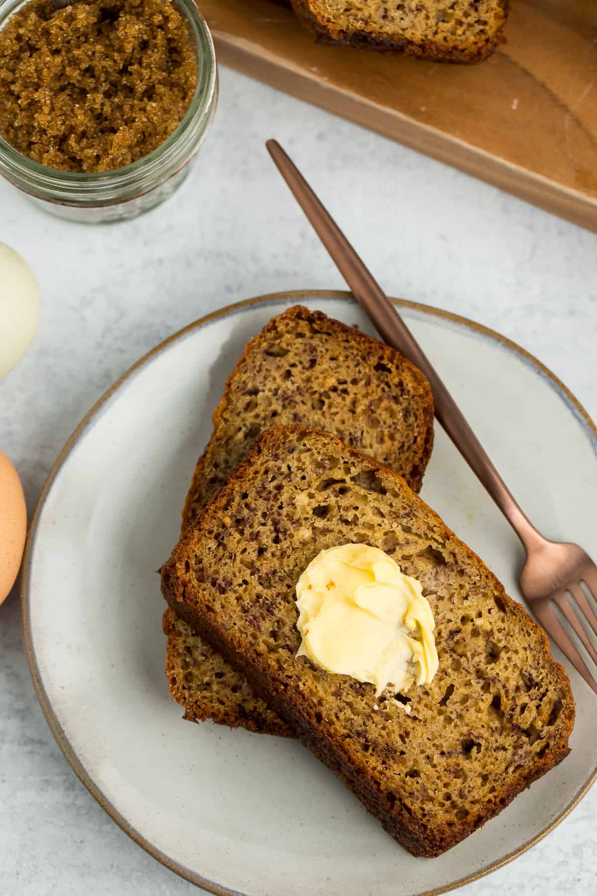 a buttered piece of banana bread on a plate with a fork.