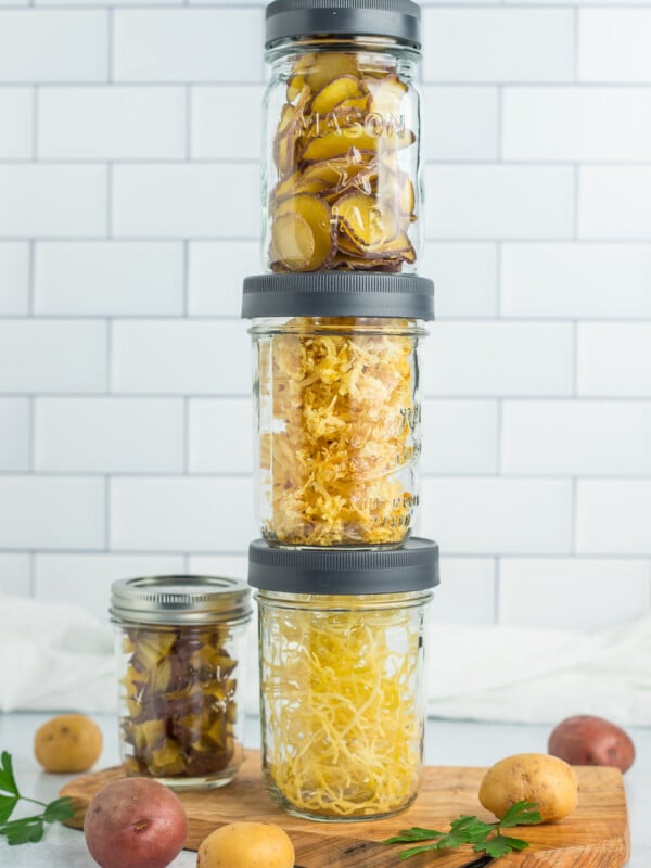 4 jars of different kinds of dehydrated potatoes stacked in front of a white tile background.