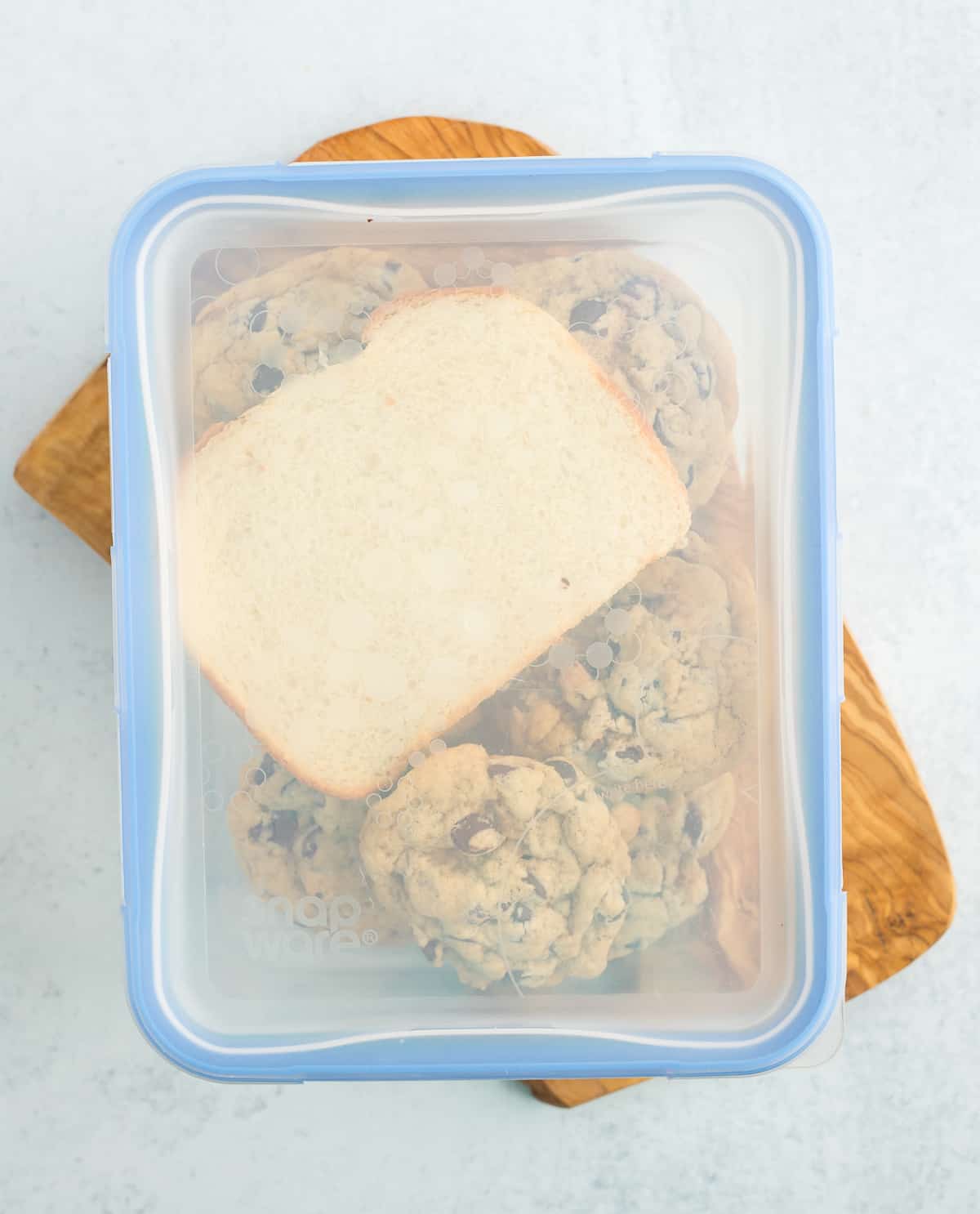 a piece of bread in a glass lidded container with cookies.