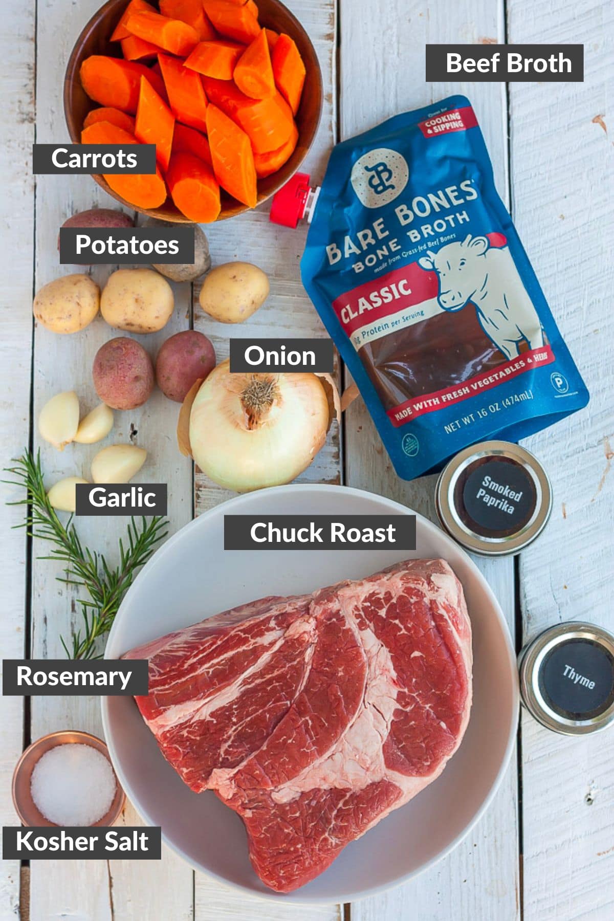 beef, broth, vegetables, spices, and other ingredients on a white wooden board.