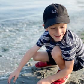 a kid in a black hat at the beach.