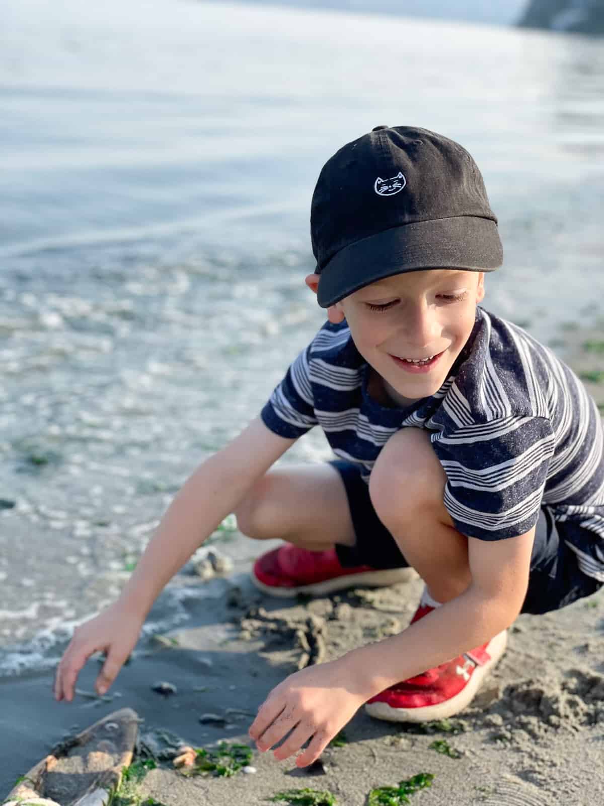 a kid in a black hat at the beach.