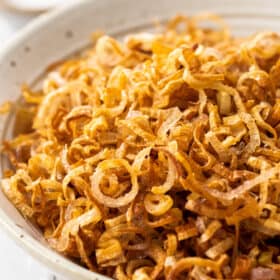 a beige bowl of fried shallots.