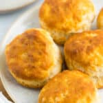 4 frozen air fryer biscuits on a grey speckled plate.