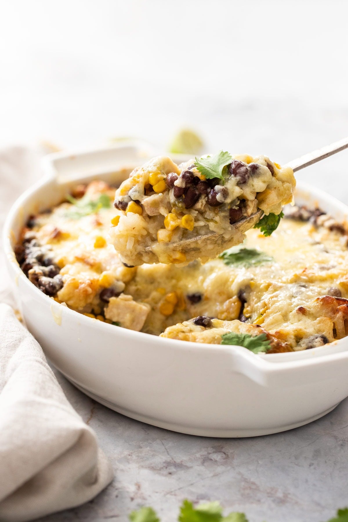 a spoon scooping a serving of leftover turkey casserole from a white baking dish.