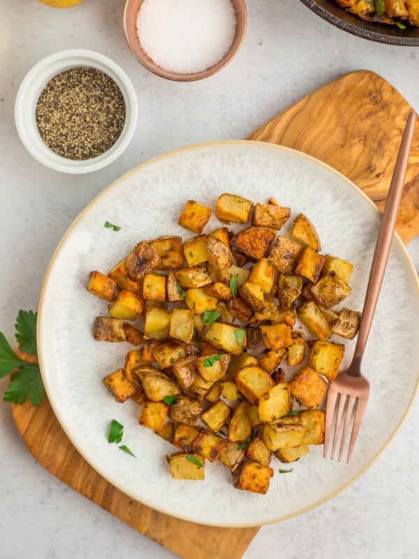 a grey plate with roasted cast iron potatoes topped with parsley.
