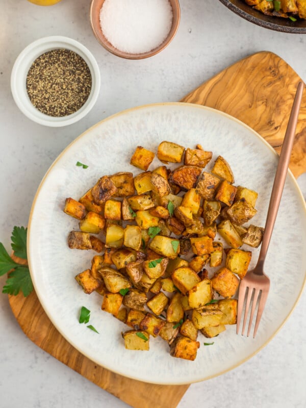 a grey plate with roasted cast iron potatoes topped with parsley.