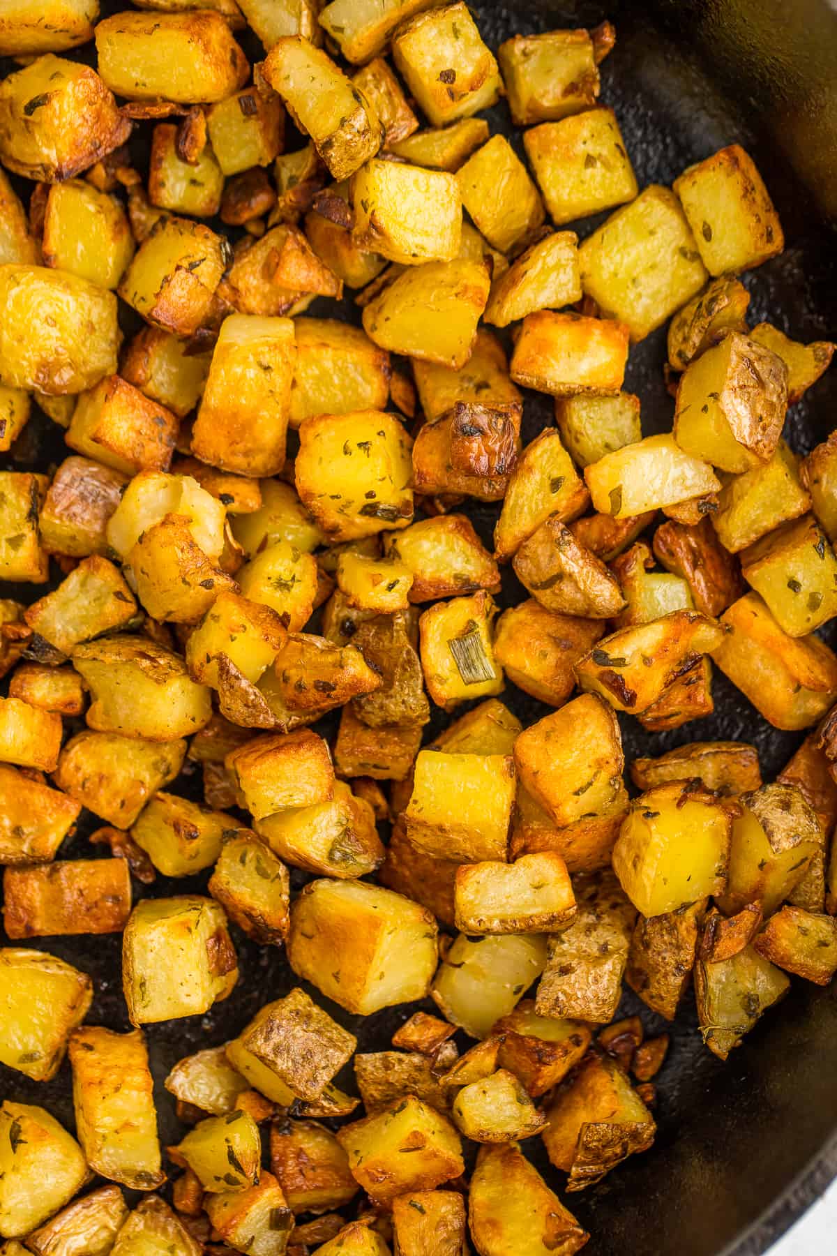 a close up of home fries in a skillet.