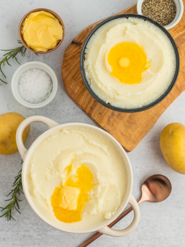 two bowls of fluffy mashed potatoes with melting butter.
