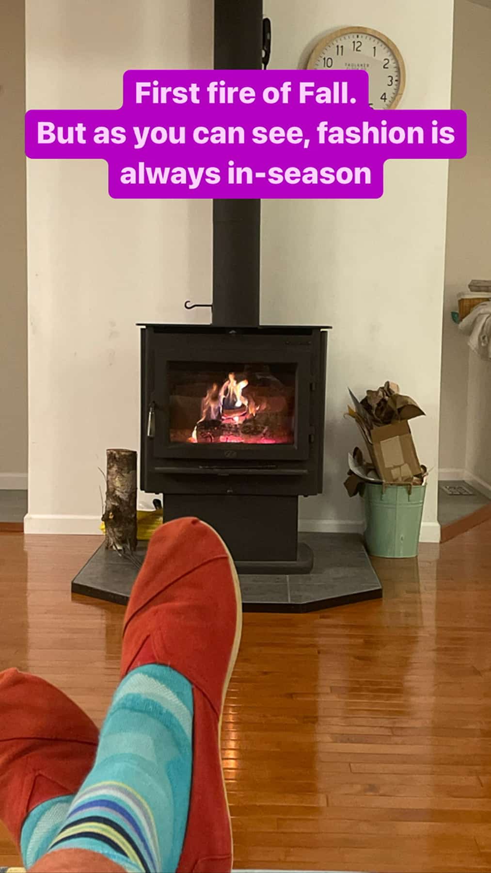 a woman wearing teal socks with red shoes in front of a lit woodstove.