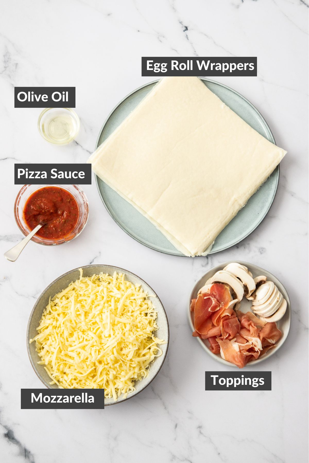 marinara, mozzarella, won ton wrappers and other ingredients on a marbled board.