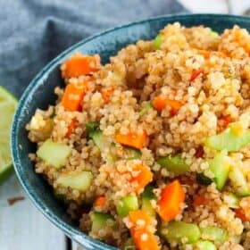 a green bowl with quinoa salad and vegetables.