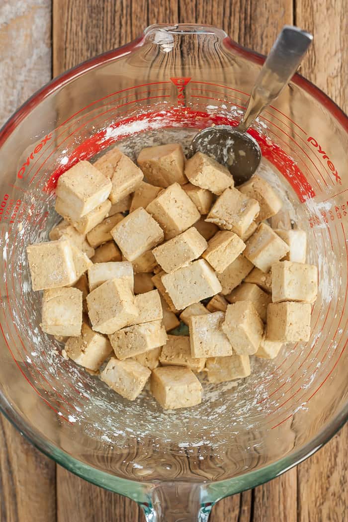 a bowl of seasoned tofu cubes with a spoon in it.