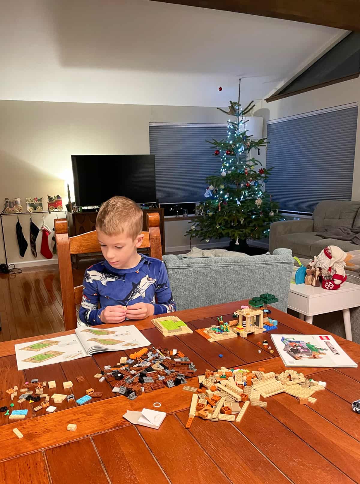 a boy building a lego set at a table.