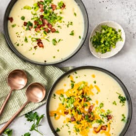Two bowls of Instant Pot Potato Soup topped with bacon, onions, and cheese.