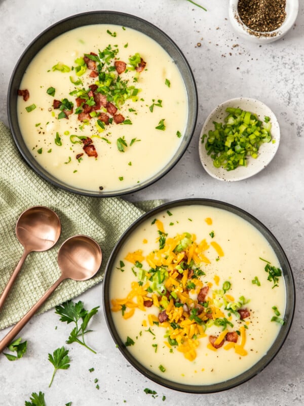 Two bowls of Instant Pot Potato Soup topped with bacon, onions, and cheese.