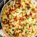 a white skillet filled with chicken bacon ranch casserole topped with chopped parsley.