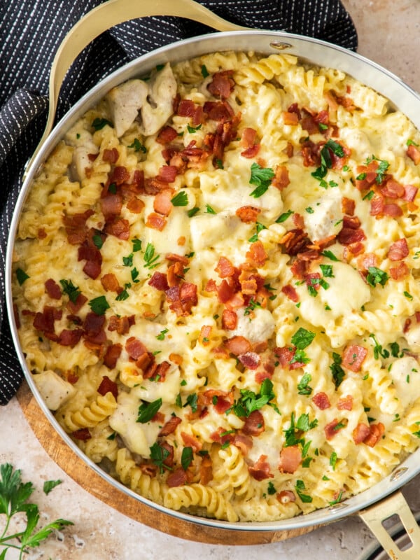a white skillet filled with chicken bacon ranch casserole topped with chopped parsley.
