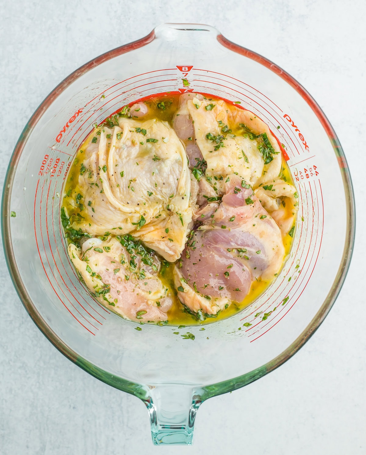 unbaked chicken thighs in a glass bowl with a homemade marinade.