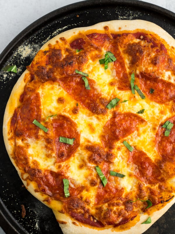 an overhead shot of a pepperoni pizza on a black pizza stone.