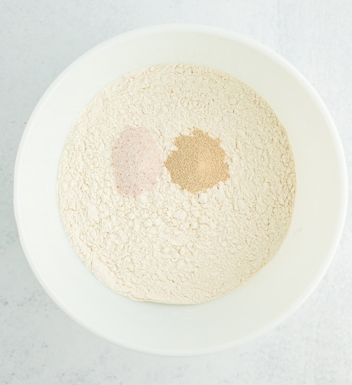 flour, yeast, and salt in a white bowl.