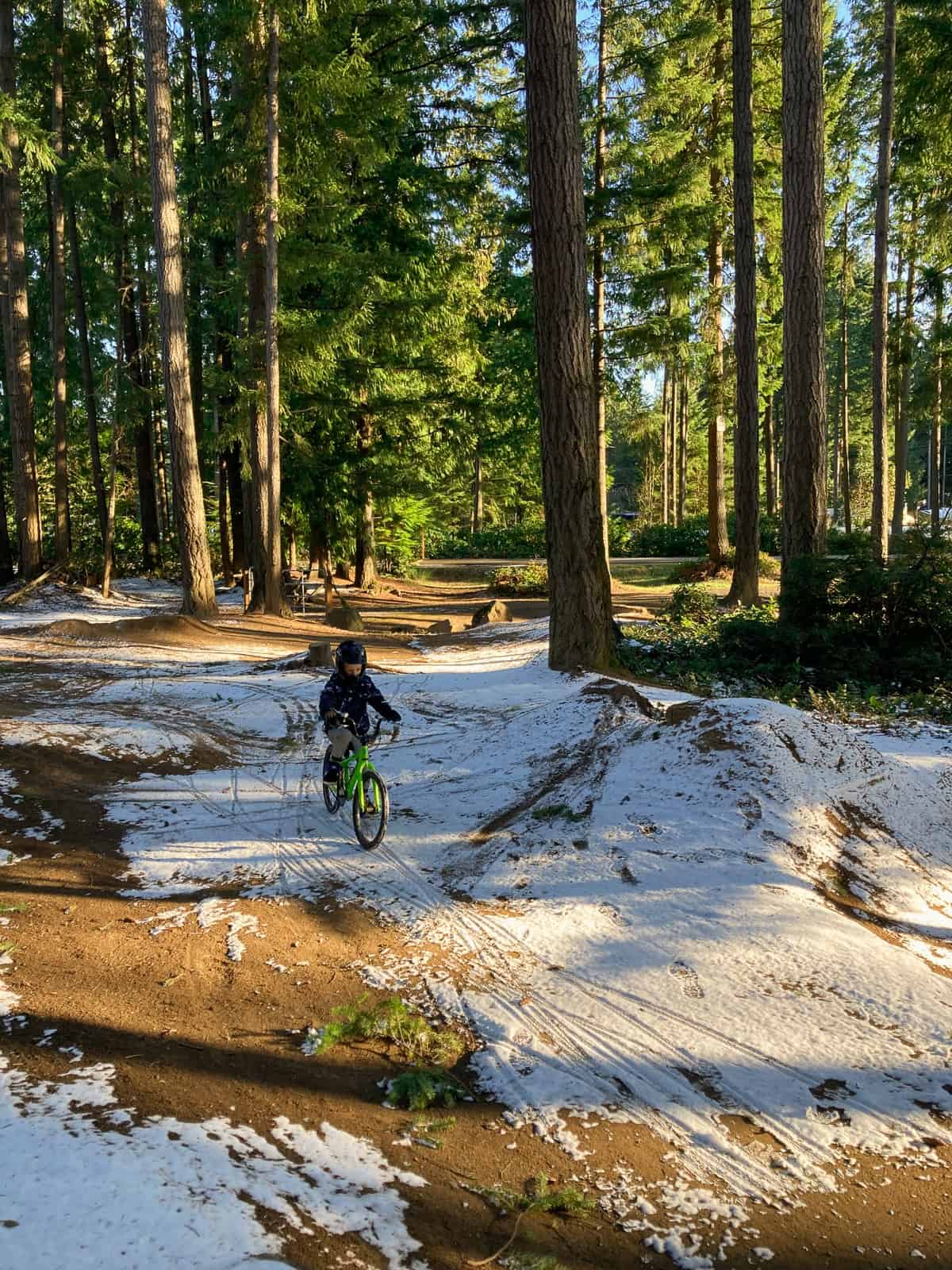 a boy on a bike in the woods with snow.