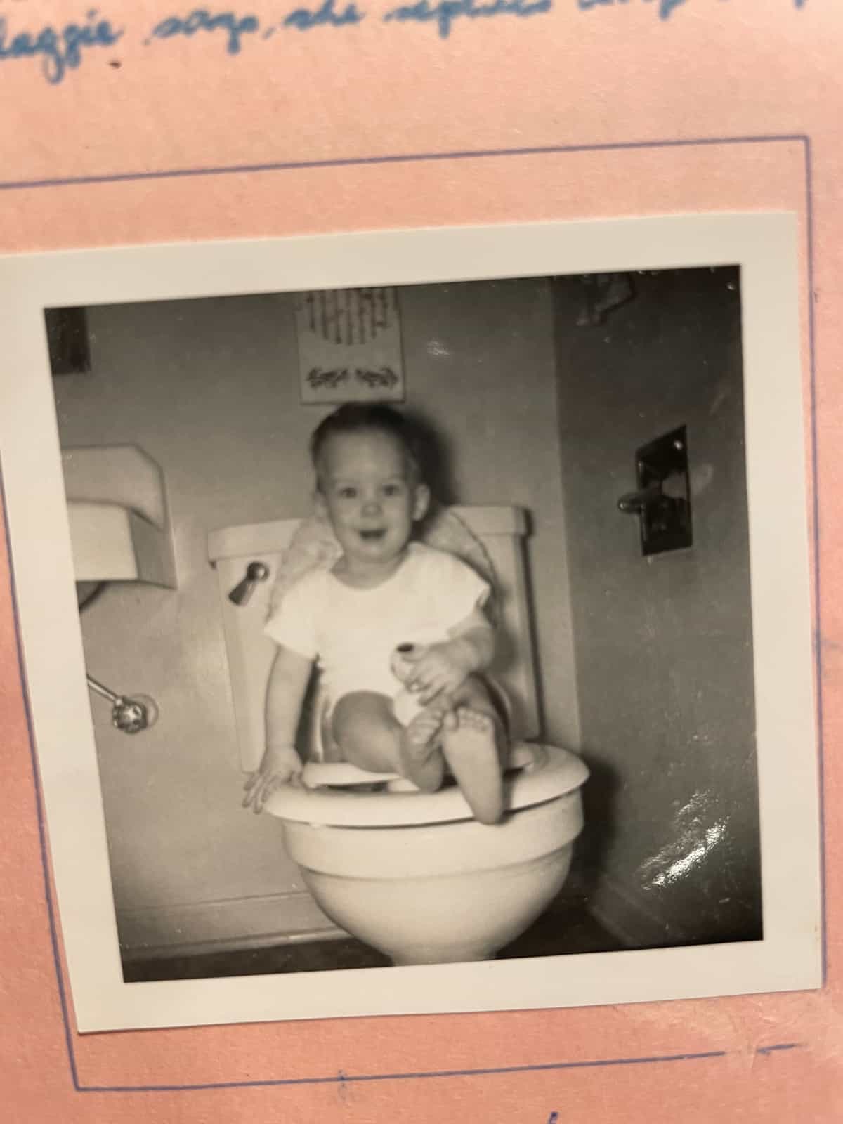 a picture of a baby sitting on a toilet.