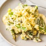 a portion of asparagus casserole on a beige plate with a fork.