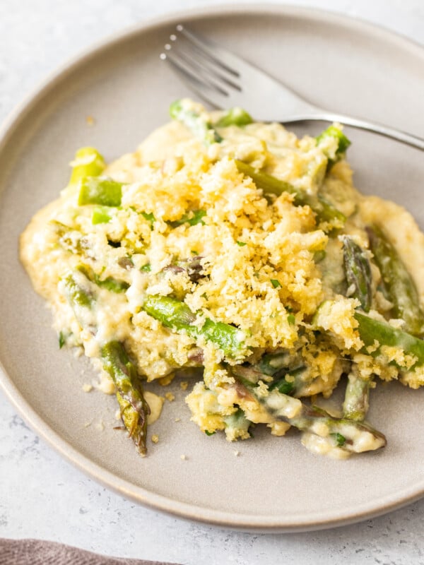 a portion of asparagus casserole on a beige plate with a fork.