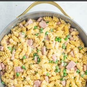 rotini, diced ham, and peas in a skillet topped with fresh chopped parsley.