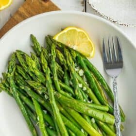asparagus on a white plate with a lemon.
